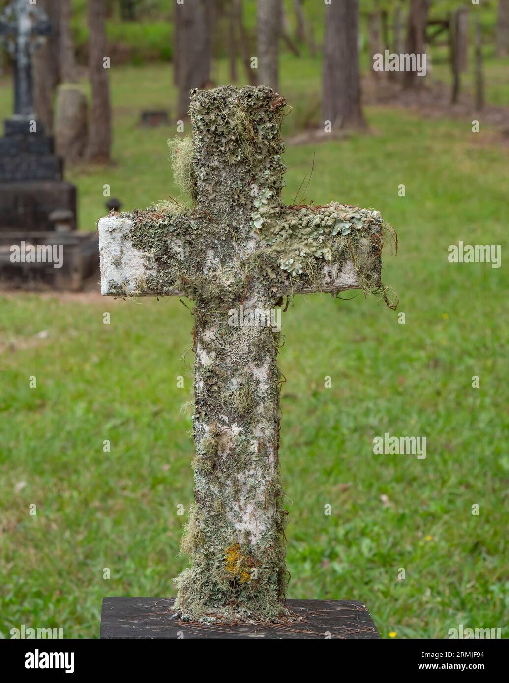 Croix chrétienne en marbre incrustée de lichen dans un ancien cimetière. Banque D'Images