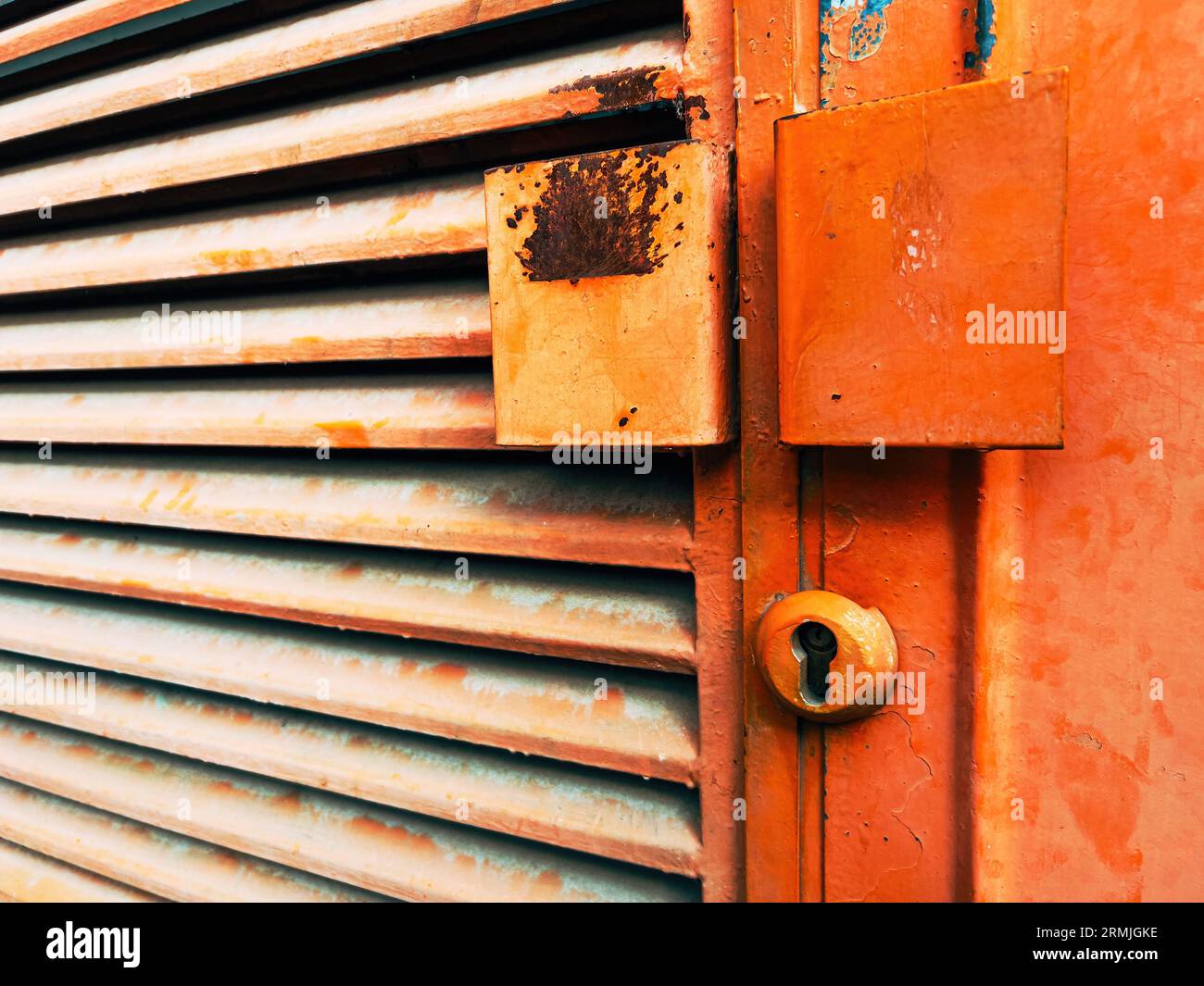 Ancienne porte industrielle métallique peinte en orange avec des marques de corrosion, mise au point sélective Banque D'Images