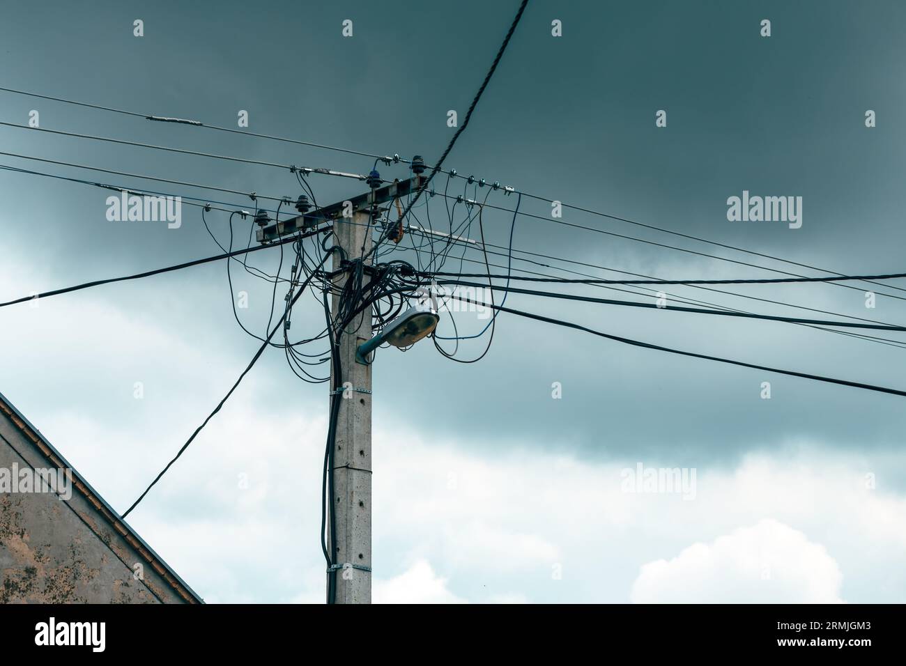 Ancien service public d'électricité et poteau de lumière de rue avec des câbles et des fils contre le ciel dramatique, mise au point sélective Banque D'Images