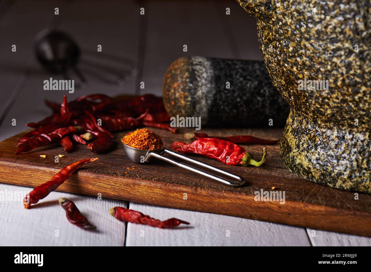 Cuillère à mesurer avec poivre moulu sur une planche à découper, poivrons séchés, mortier à noyau et pilon Banque D'Images