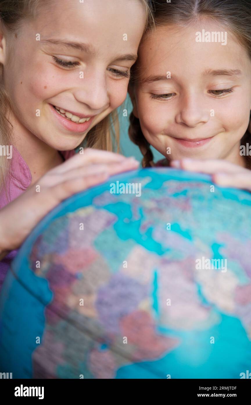 Deux jeunes filles touchant et tournant un globe terrestre Banque D'Images