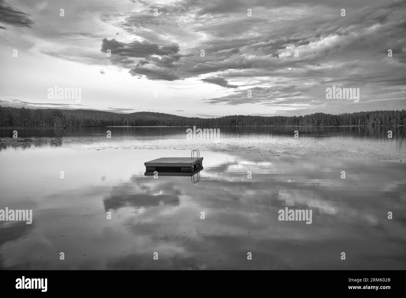 Île de baignade en Suède sur un lac au coucher du soleil en noir et blanc. Nuages réfléchis dans l'eau. Natation plaisir en vacances avec loisirs en Scandinavie Banque D'Images