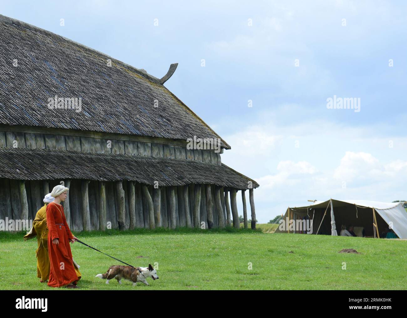 Des femmes et une petite fille habillées de vêtements viking traditionnels marchent près de la maison viking reconstruite, au musée Trelleborg. Trelleborg , Danemark. Banque D'Images