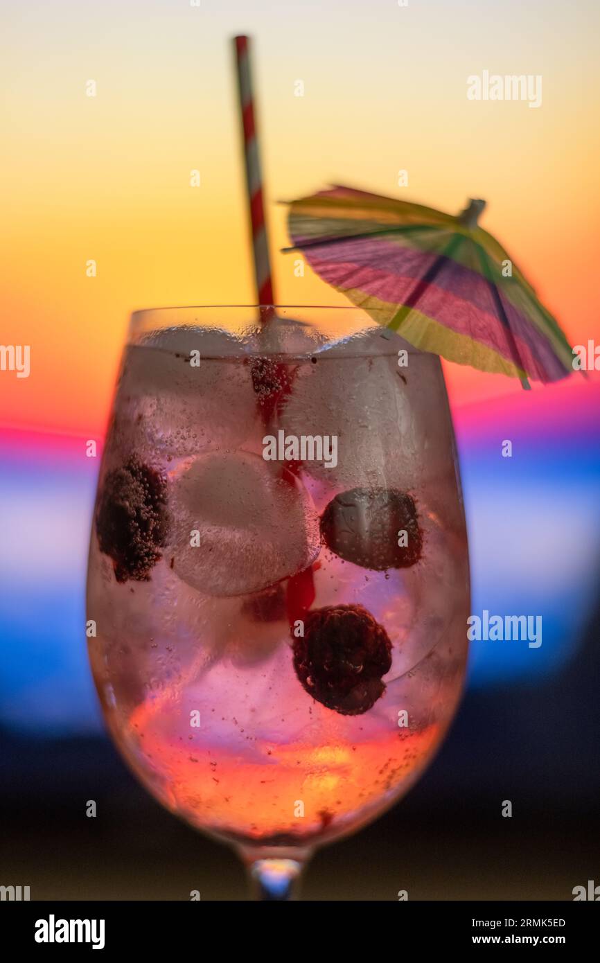 Cocktail sur le comptoir d'Un bar de plage au coucher du soleil. Boisson alcoolisée avec fruits de baies, avec paille et parapluie Banque D'Images