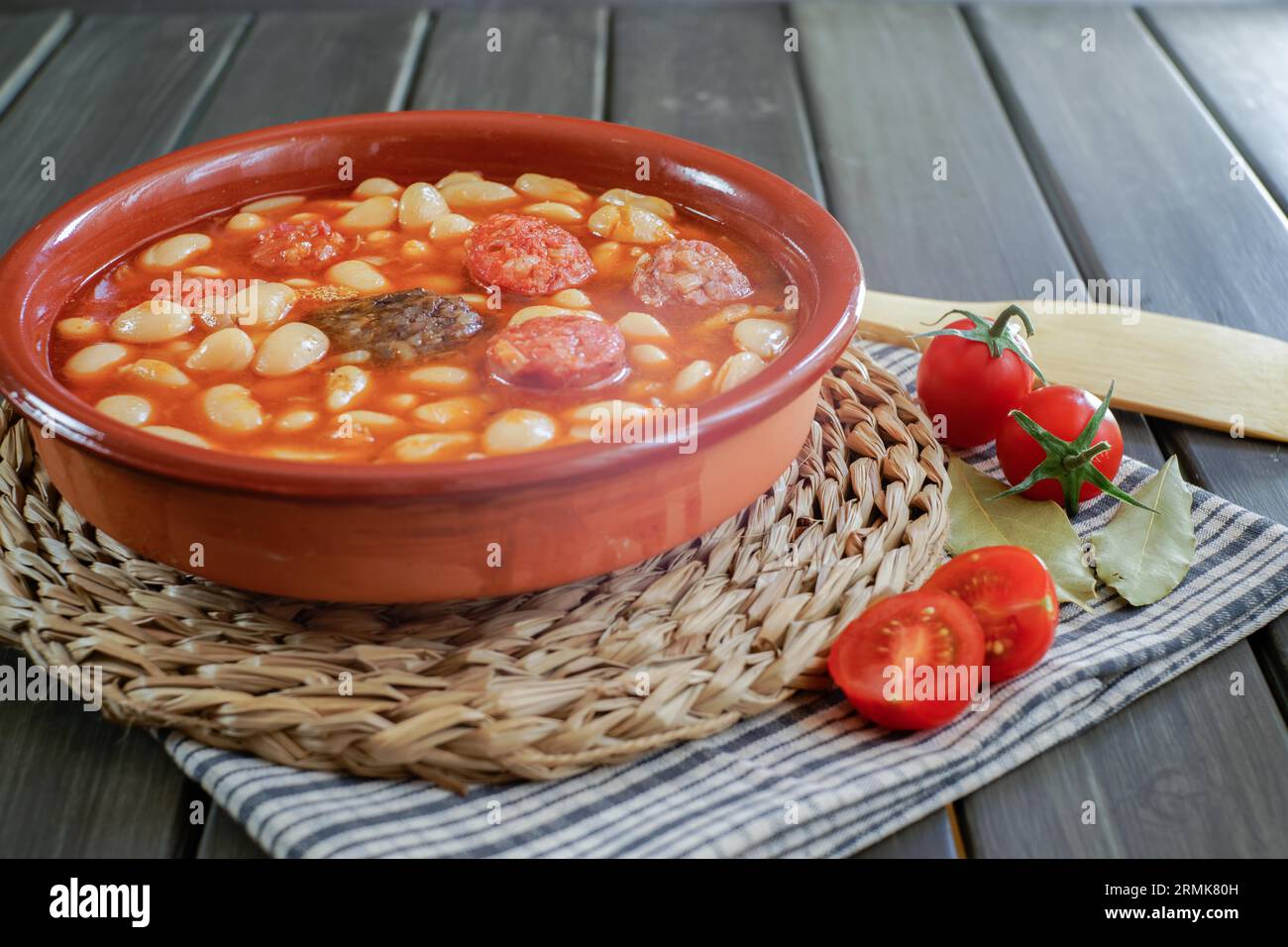 Haricots cuits avec chorizo et saucisse de sang dans un pot d'argile avec tomates et feuilles de Laurier Banque D'Images