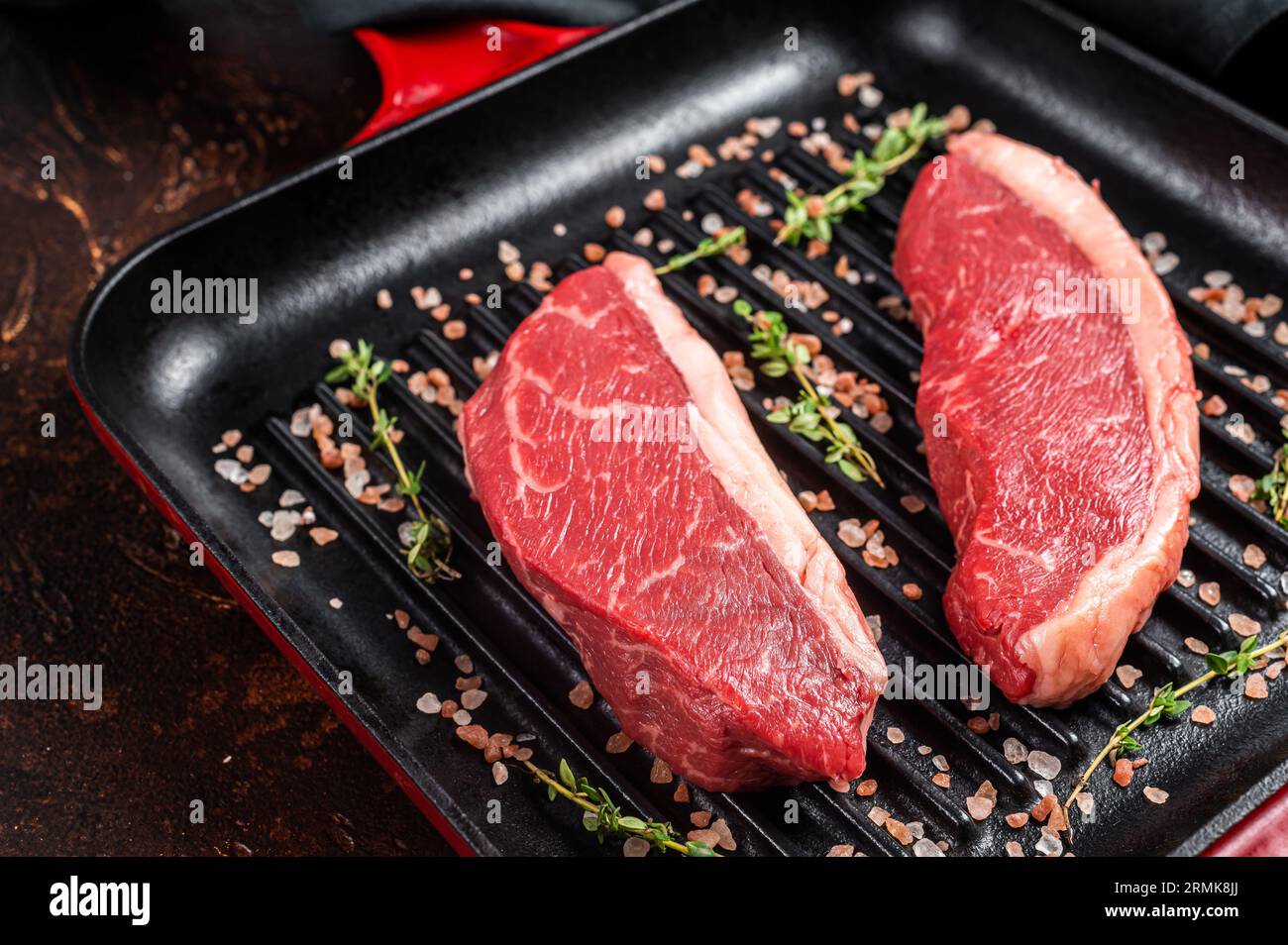 Steak de croupe de chapeau cru, viande de bœuf marbrée sur une poêle à griller. Arrière-plan sombre. Vue de dessus. Banque D'Images