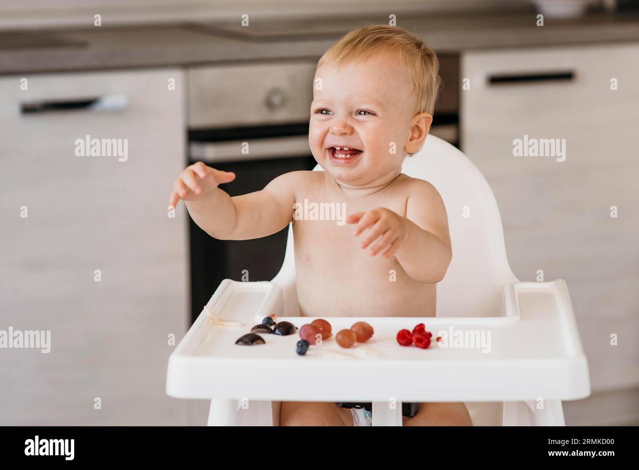 Chaise haute bébé Smiley choisir ce que les fruits mangent Banque D'Images