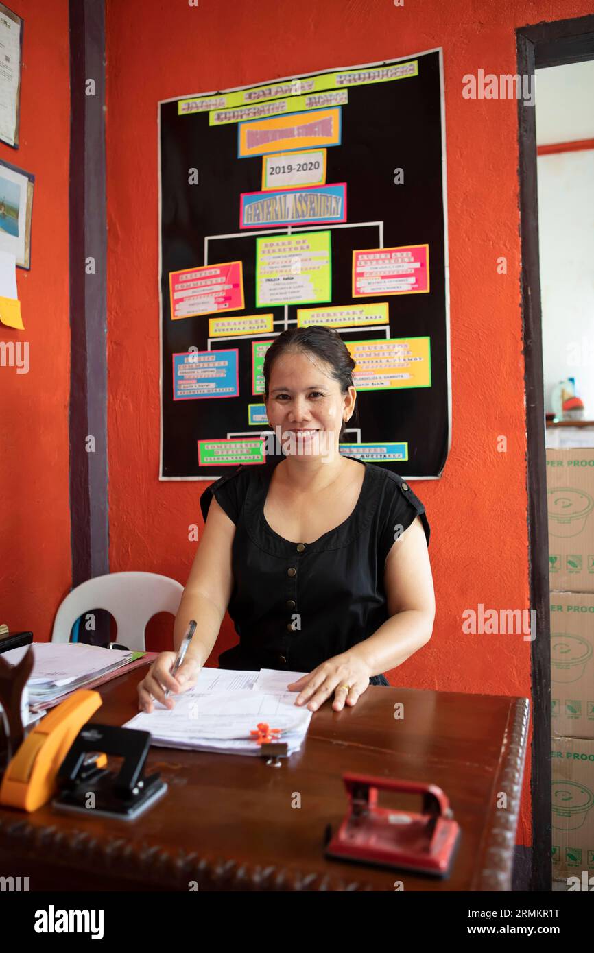Femme, 44 ans, assise à un bureau dans le bureau de la coopérative Jagna Calamay Makers, qui fabrique Calamay, une spécialité philippine à base de gluant Banque D'Images