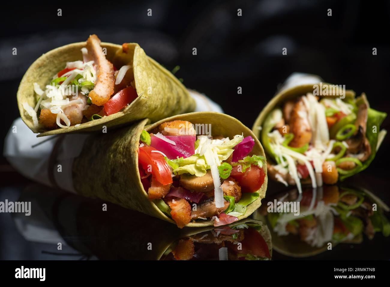 Tortillas végétaliennes maison avec haricots rouges, patates douces, tomates et guacamole avec sauces et épices sur fond noir. Banque D'Images