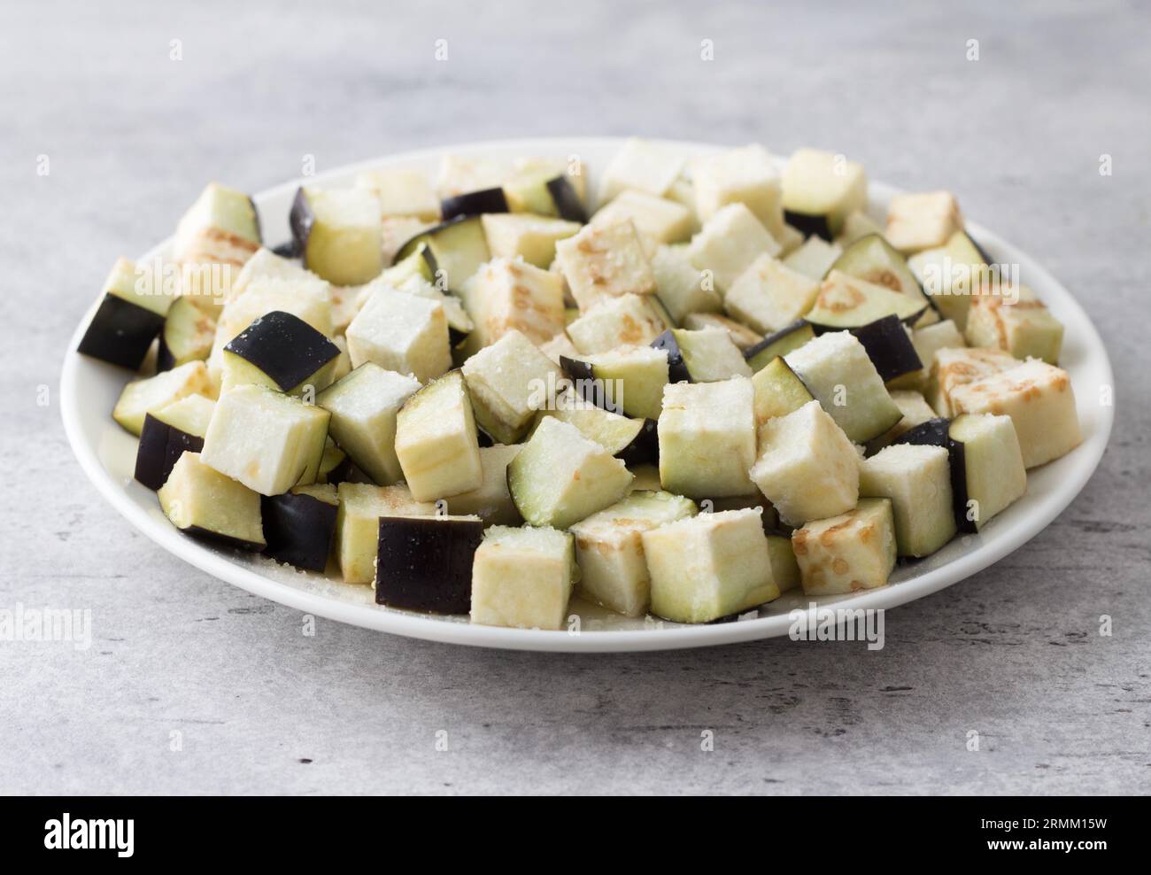 Aubergine fraîche sur une planche de bois, un bol de sel et un couteau sur un fond gris texturé, gros plan. Cuisiner de délicieux plats végétaliens. Banque D'Images