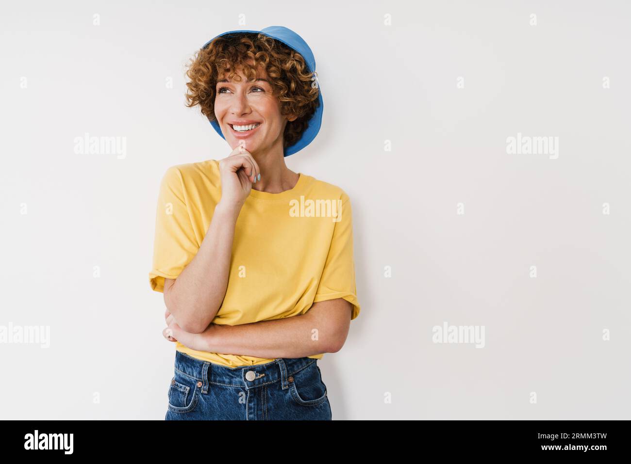 Femme de gingembre d'âge moyen portant panama souriant tout en se tenant isolée au-dessus d'un mur blanc Banque D'Images