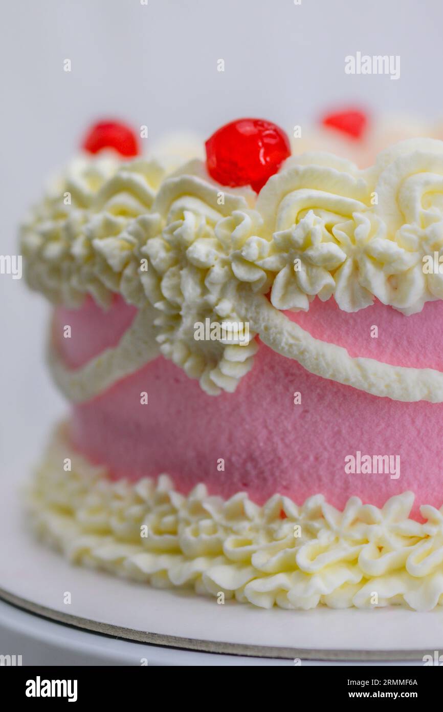 Cupcake rouge rose pour la célébration d'anniversaire isolé sur blanc, lissant topper avec spatule, portant des gants dans la cuisine professionnelle Banque D'Images