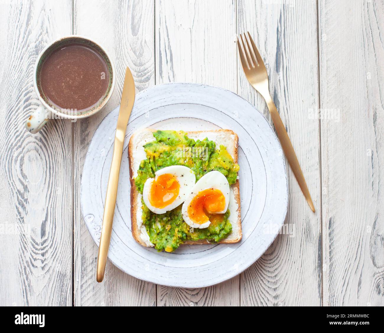 Sandwich aux œufs d'avocat avec une tasse de cacao chaud. Concept de petit déjeuner léger et sain. Toasts de grains entiers avec de la purée d'avocat et des œufs frits et des graines de citrouille Banque D'Images