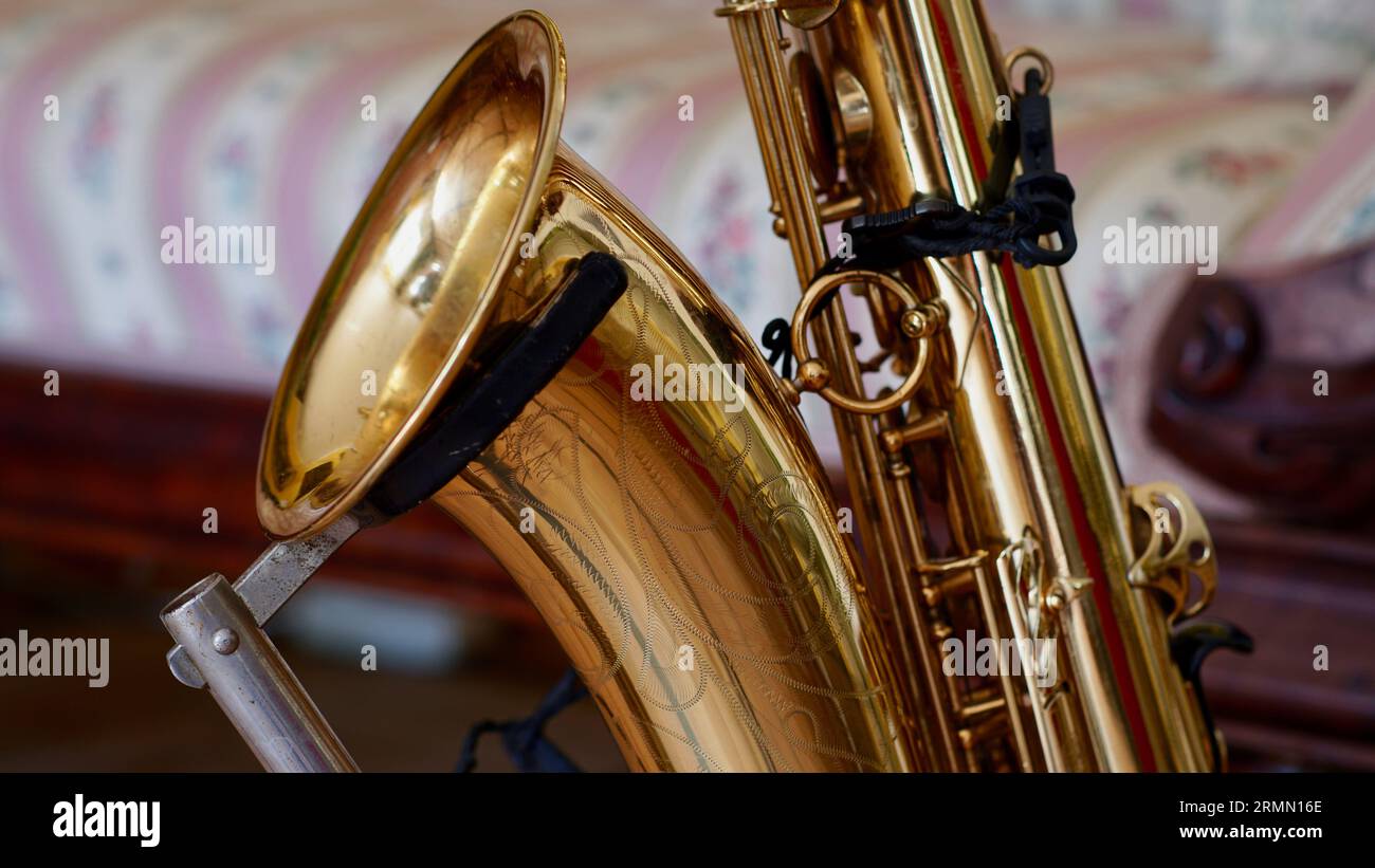 Détail d'un saxophone ténor sur un support devant un canapé. Banque D'Images