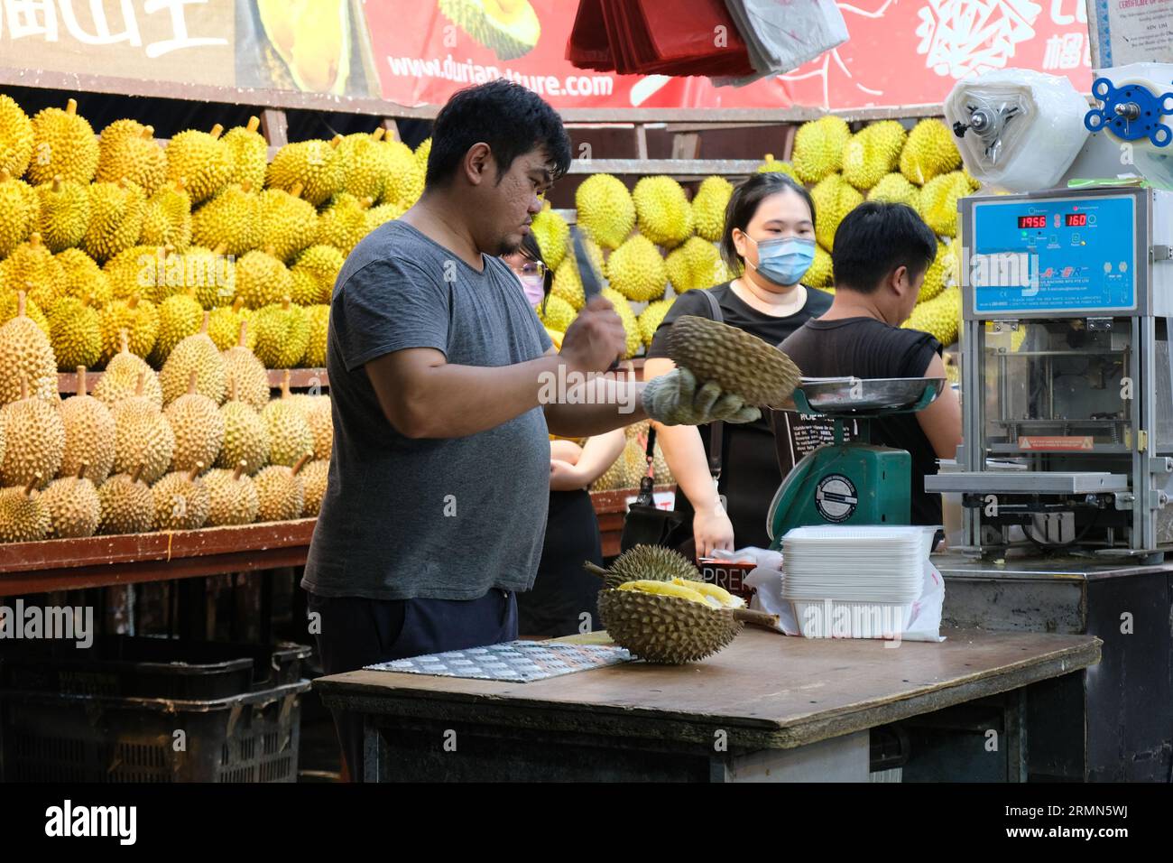 Le vendeur de durian hache les fruits tropicaux piquants dans un étal de rue dans le quartier de Geylang à Singapour. 24/09/2022 Banque D'Images