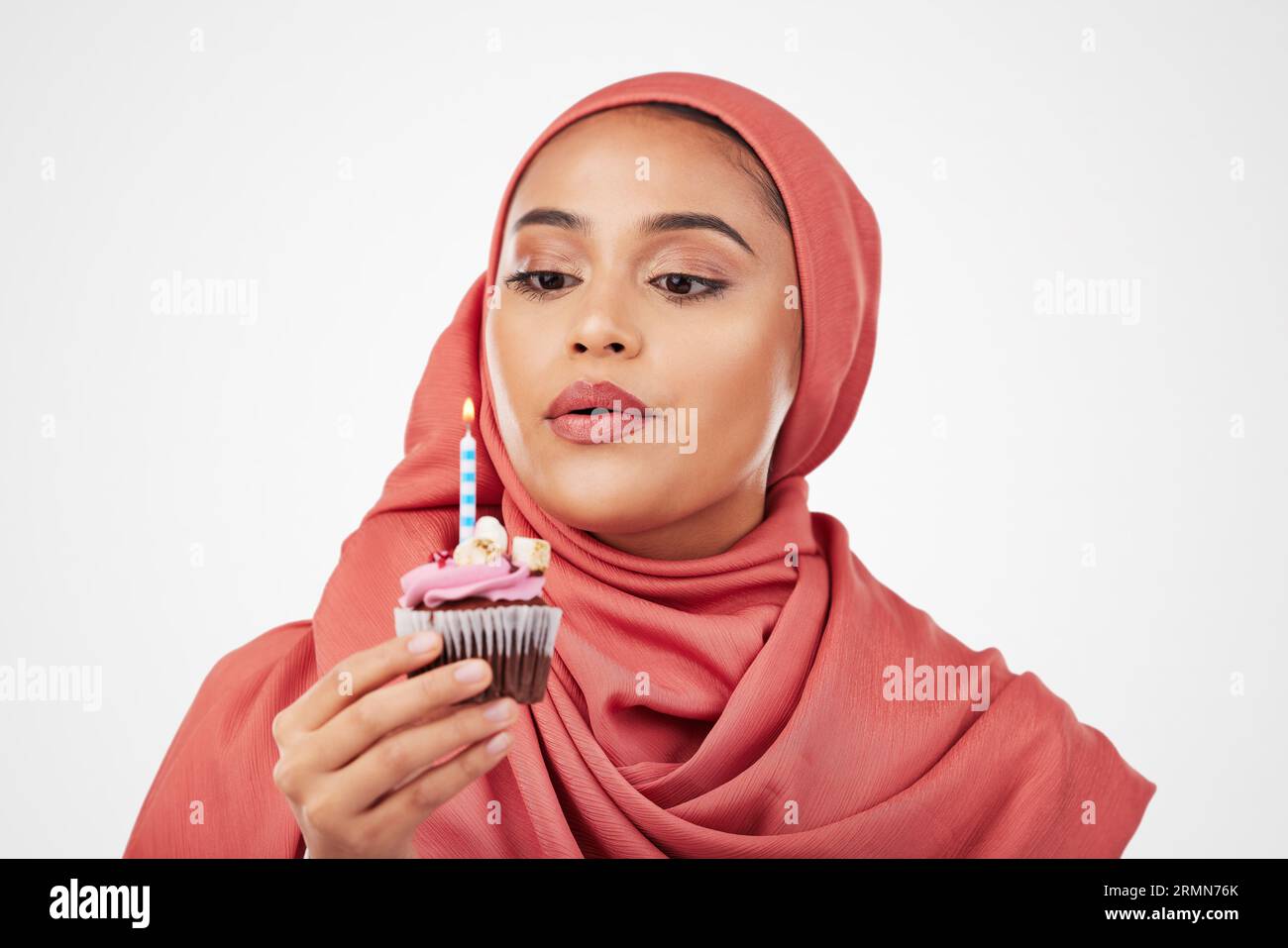 Musulman, femme et cupcake avec bougie, souhait d'anniversaire et célébration avec dessert isolé sur fond blanc. Flamme soufflée, gâteau et bonbons, hijab Banque D'Images