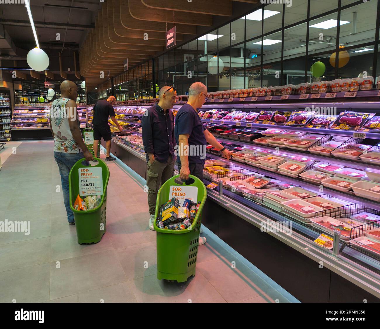 Les hommes comparent les prix de la viande, dans la section boucherie d'un grand supermarché à Rome, en Italie Banque D'Images