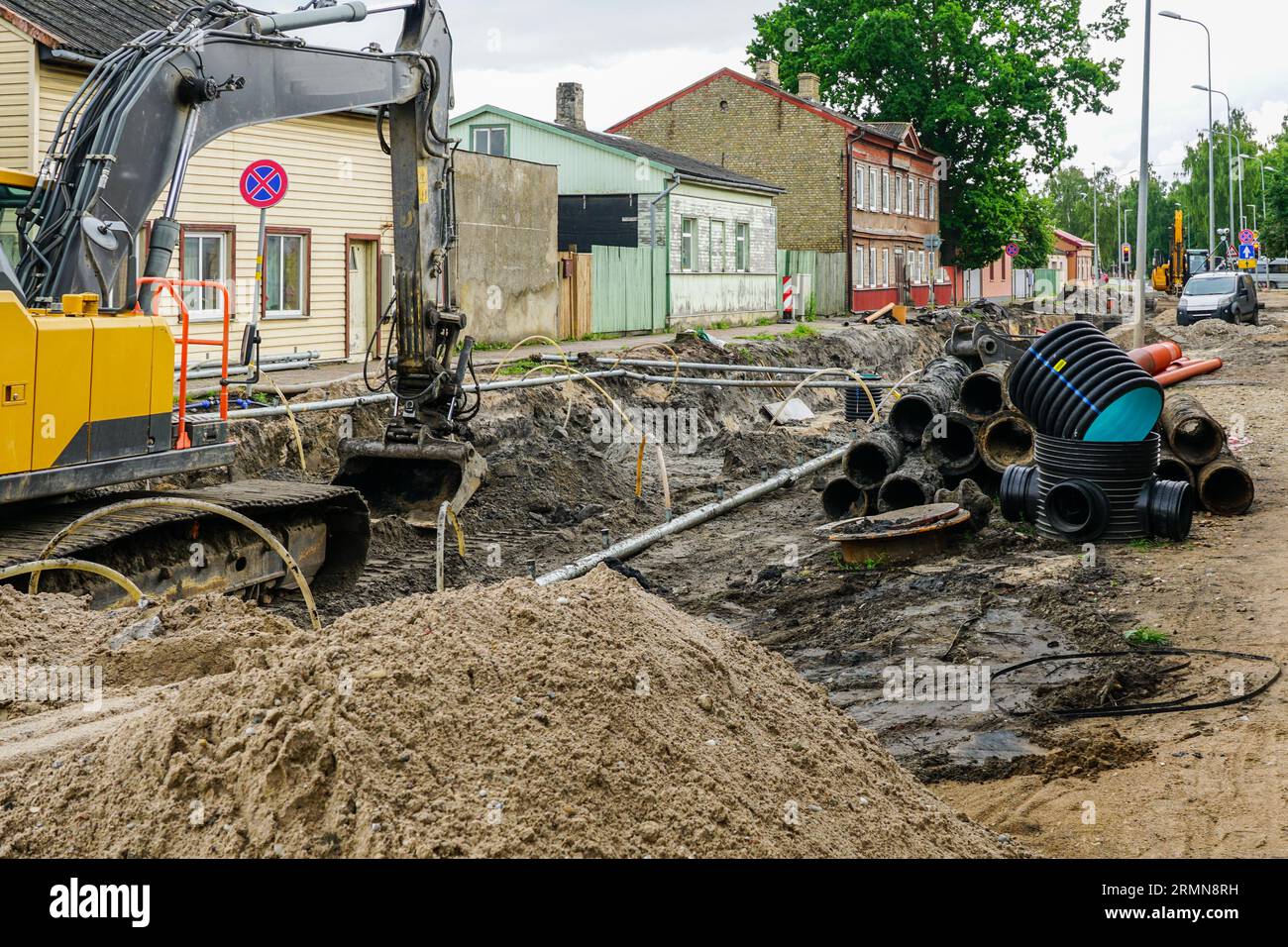 Vue de reconstruction de rue avec tranchée profonde, vieux et nouveaux tuyaux souterrains, nouveau puits en plastique vertical Banque D'Images