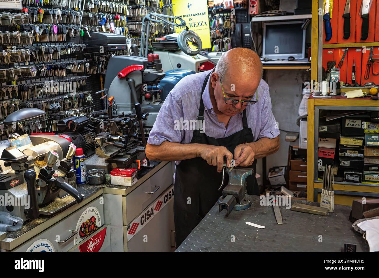 Un broyeur à couteaux âgé et expert dans son atelier broie une paire de ciseaux sur la meule de pierre. Ascoli Piceno, région des Marches, Italie, Europe Banque D'Images