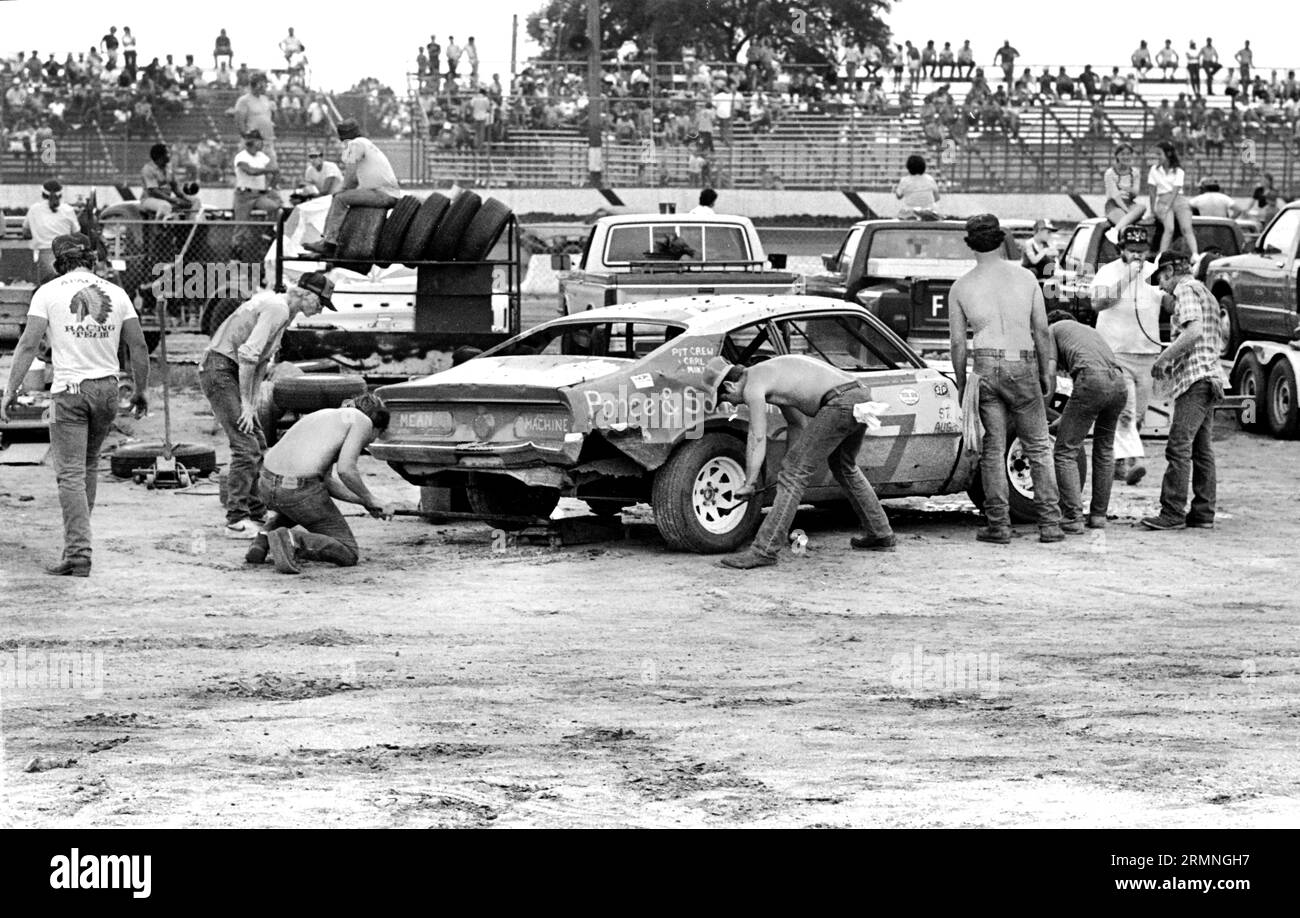 Les équipages amateurs de course de stock-car travaillent sur leurs voitures lors d'un arrêt au stand au Volusia Speedway à Barberville, en Floride, lors d'une course en 1984. Banque D'Images