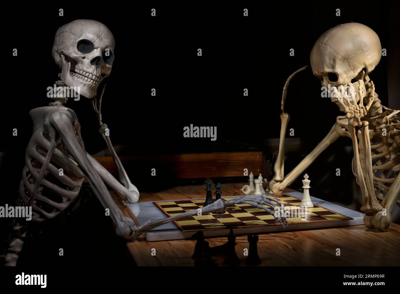 Jeu d'échecs mis en place par deux squelettes d'Halloween sur une table en bois Banque D'Images