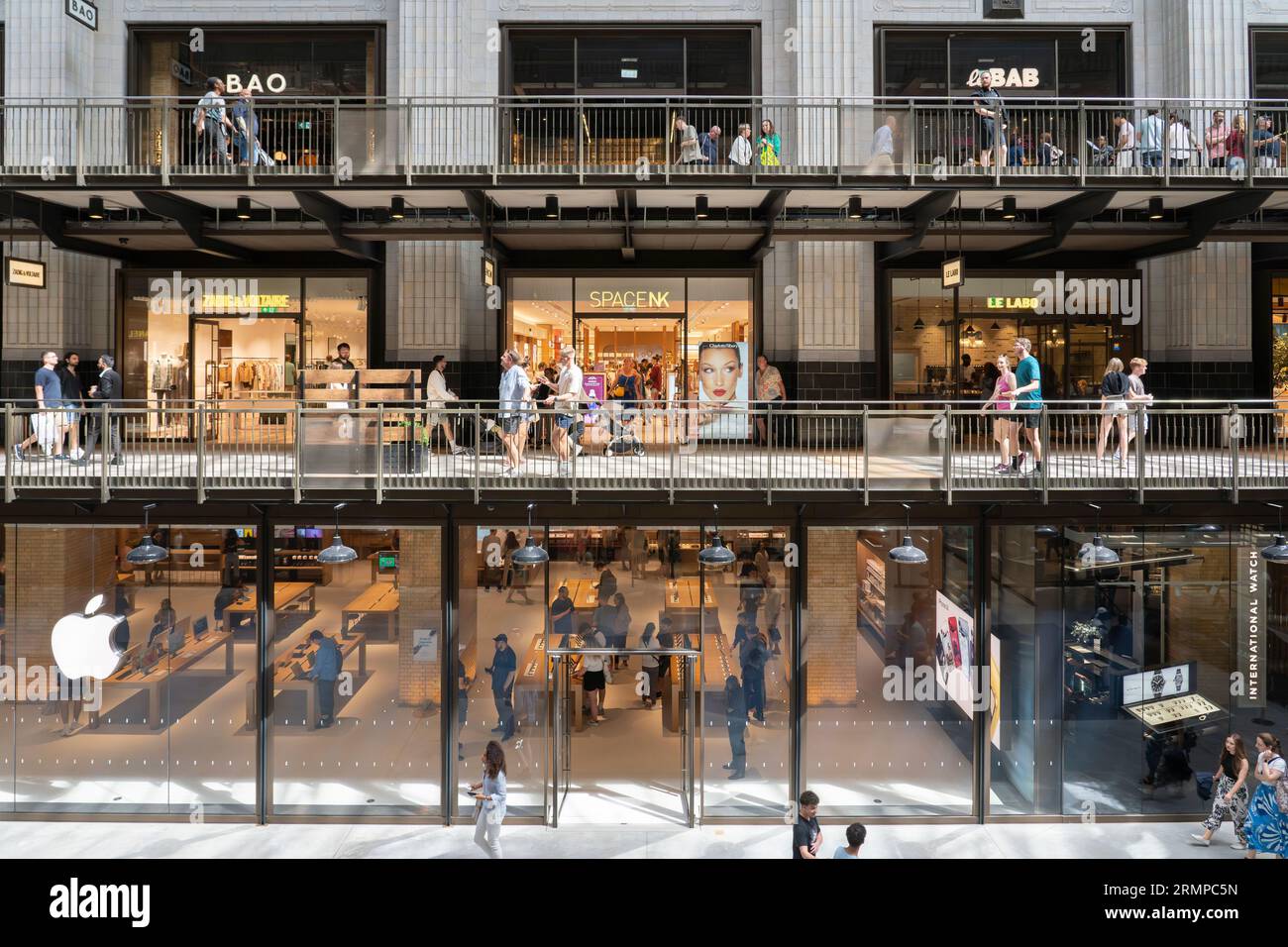 Les gens qui font leurs courses dans un Apple Store et dans d'autres magasins à différents niveaux dans le Battersea Power Station turbine Hall A. Londres, Angleterre Banque D'Images