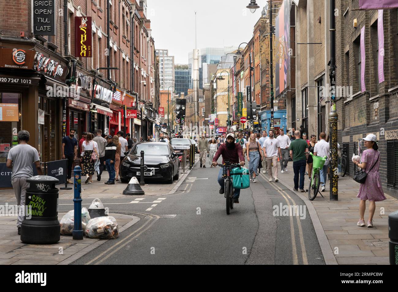 Les gens marchent et font du vélo le long de Brick Lane - une rue célèbre dans l'East End de Londres et le cœur de la communauté bangladaise du pays. ROYAUME-UNI Banque D'Images