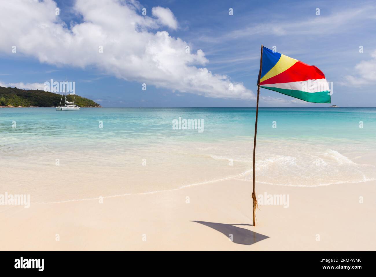 Le drapeau des Seychelles monté sur la plage agitant dans le vent par une journée ensoleillée Banque D'Images