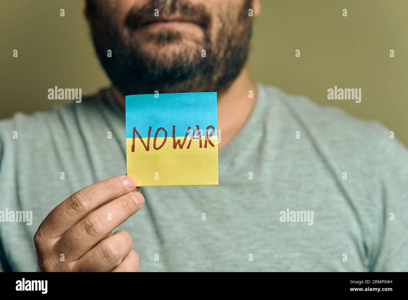 Un européen barbu tient un autocollant devant lui, sous la forme d'un drapeau ukrainien avec l'inscription no war Banque D'Images