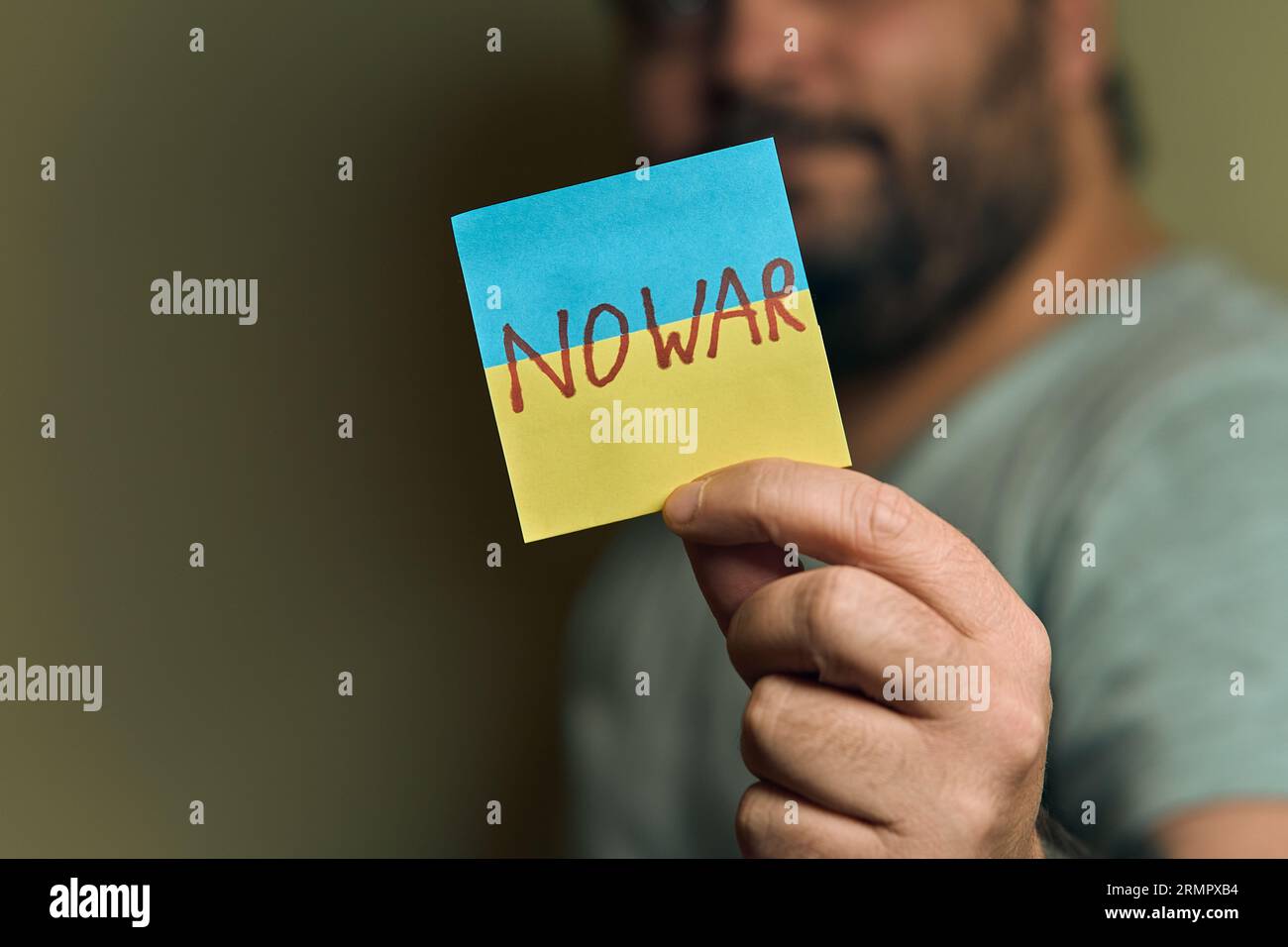 Un européen barbu tient un autocollant devant lui, sous la forme d'un drapeau ukrainien avec l'inscription no war Banque D'Images