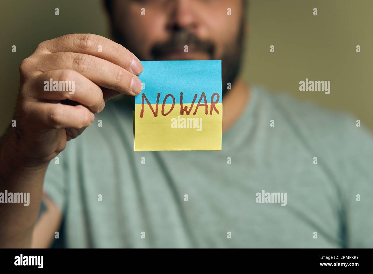 Un européen barbu tient un autocollant devant lui, sous la forme d'un drapeau ukrainien avec l'inscription no war Banque D'Images