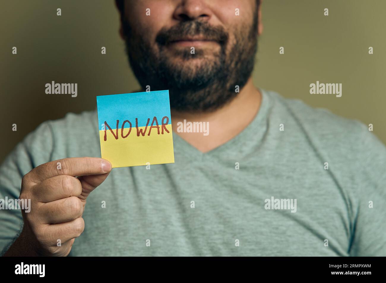 Un européen barbu tient un autocollant devant lui, sous la forme d'un drapeau ukrainien avec l'inscription no war Banque D'Images