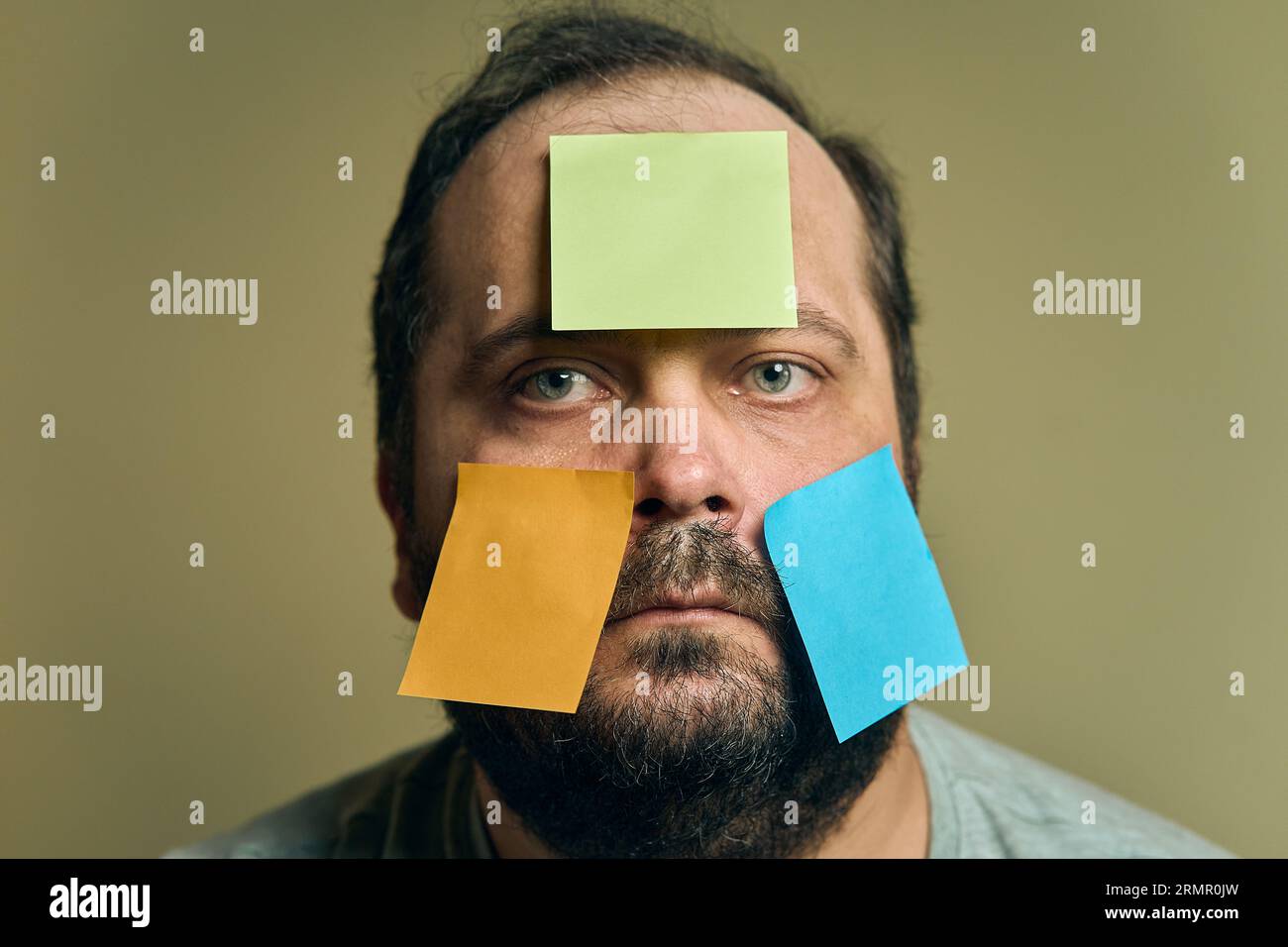 Portrait facial d'un homme avec une barbe regardant dans le cadre et recouvert d'autocollants en papier vierges Banque D'Images