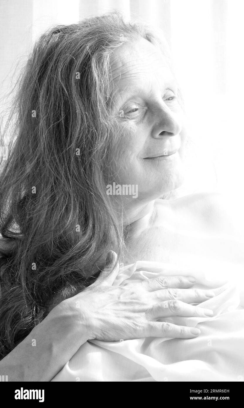 Portrait noir et blanc d'une femme rêveuse de 64 avec un fond clair. Banque D'Images