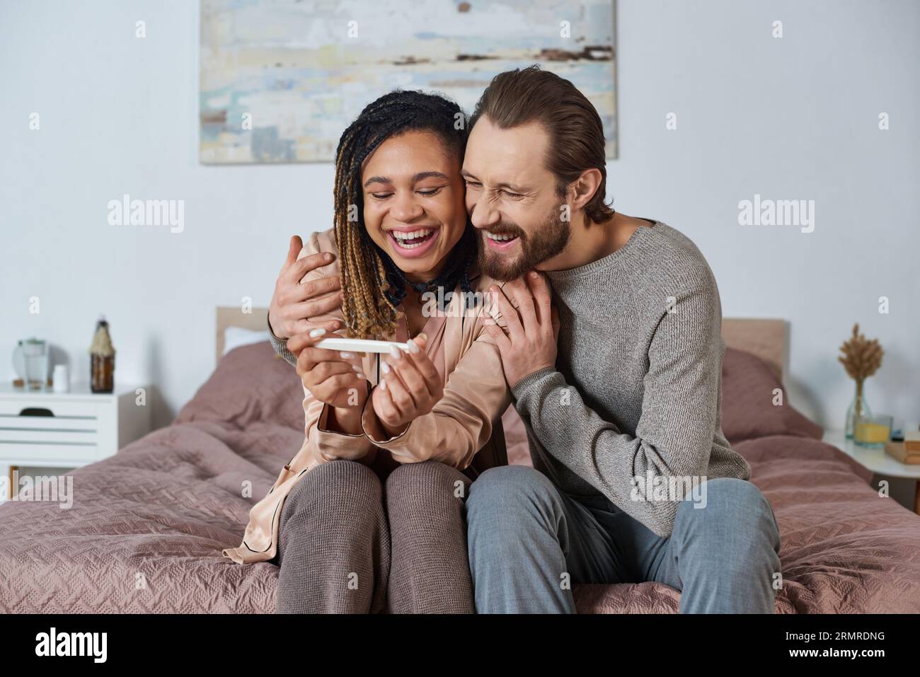 couple interracial tenant des vêtements de bébé mignons, chaussures minuscules, futurs parents, femme africaine enceinte Banque D'Images