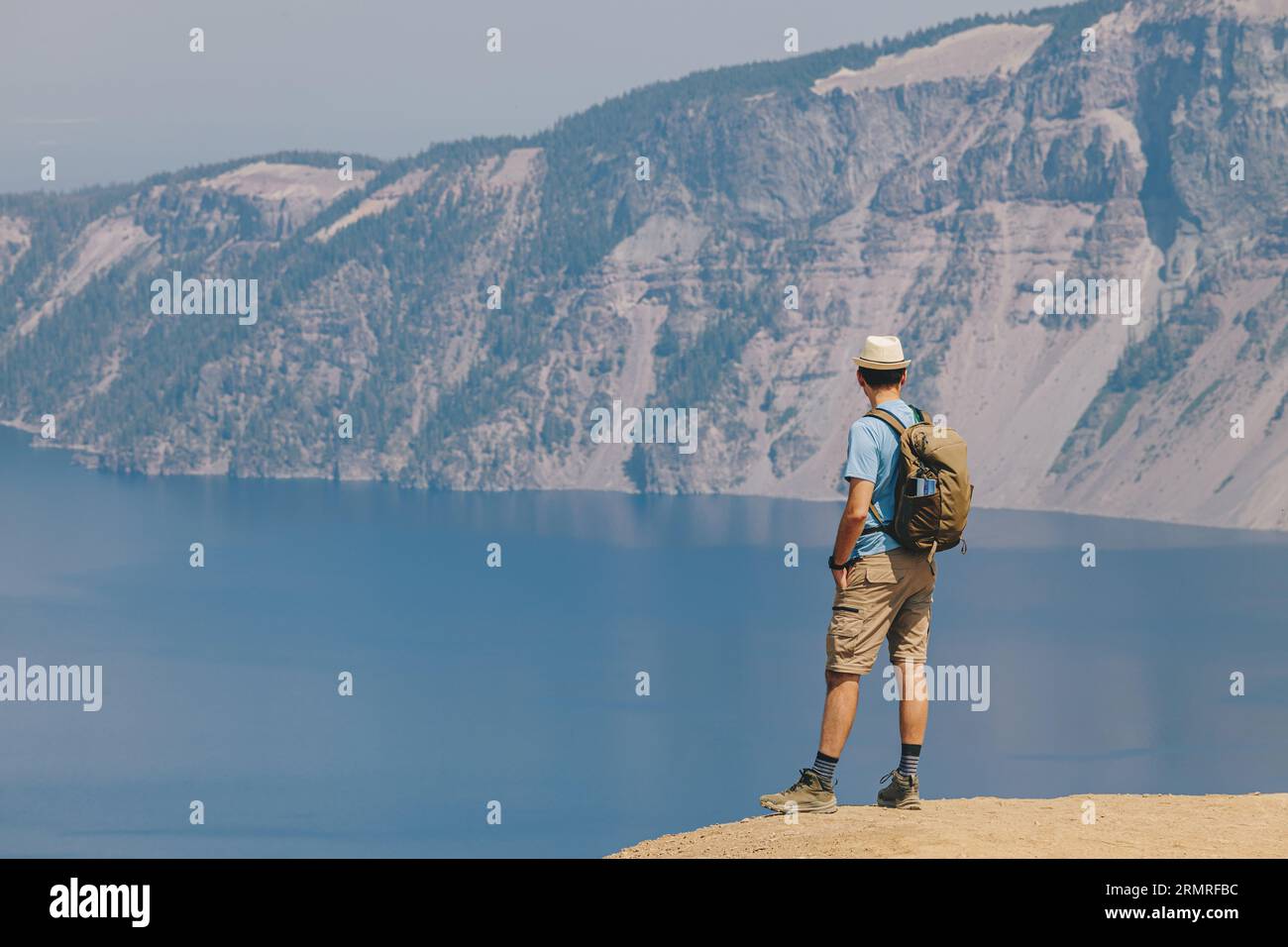 Randonnée estivale dans un parc national du lac Crater, homme avec un sac à dos debout avec vue sur la caldeira Banque D'Images