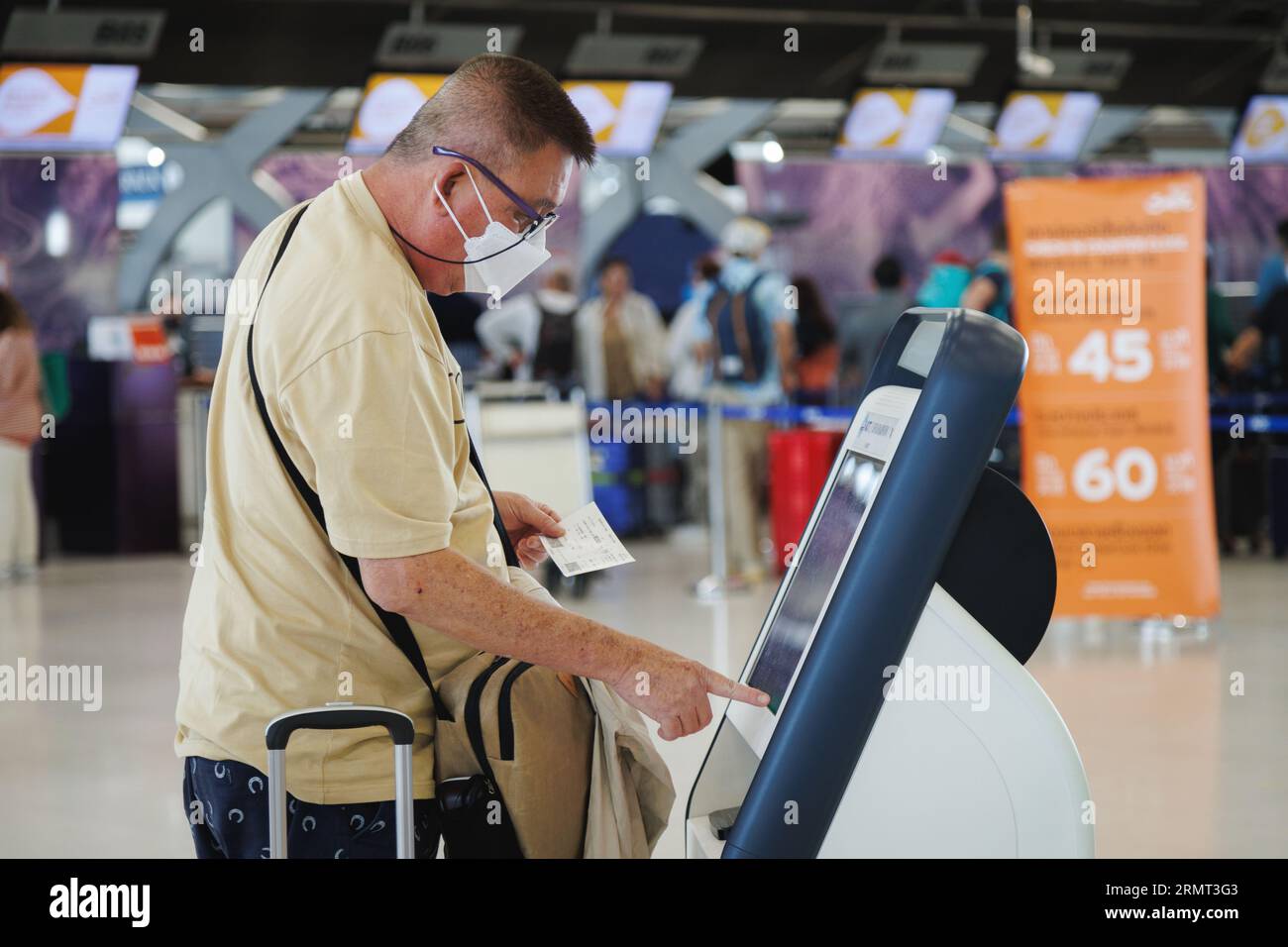 Bangkok, Thaïlande - 30 juin 2023 : le visiteur touristique chinois senior avec masque facial protecteur est en libre-service à la machine de kiosque à s. Banque D'Images