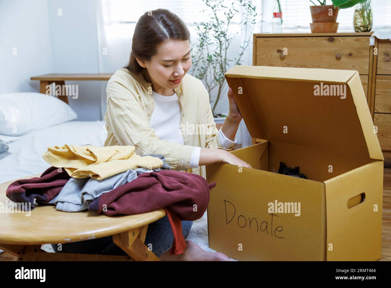 femme asiatique bénévole mettant des vêtements inutilisés dans des boîtes en carton pour don et charité. Réutilisation, recyclage, renouvelable et concept de durabilité. Banque D'Images
