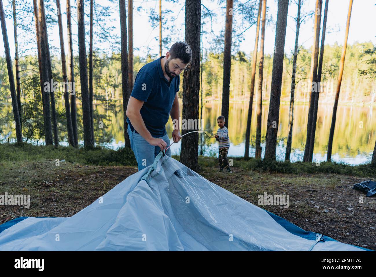 mignon garçon caucasien aidant père à monter une tente. Concept de camping familial Banque D'Images