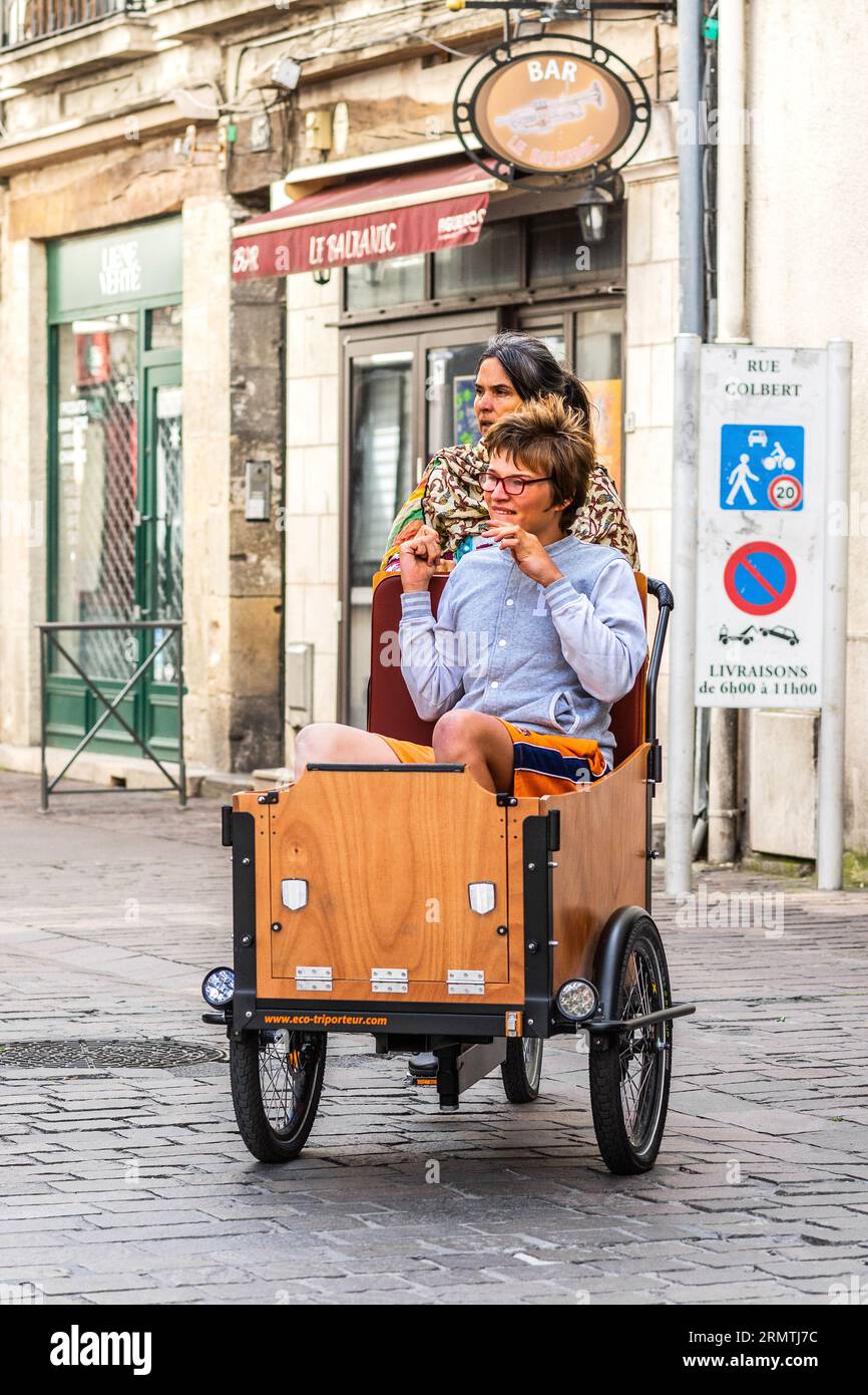 Mère et enfant partiellement handicapé roulant sur un vélo cargo à assistance électrique Eco-triporteur - Tours, Indre-et-Loire (37), France. Banque D'Images