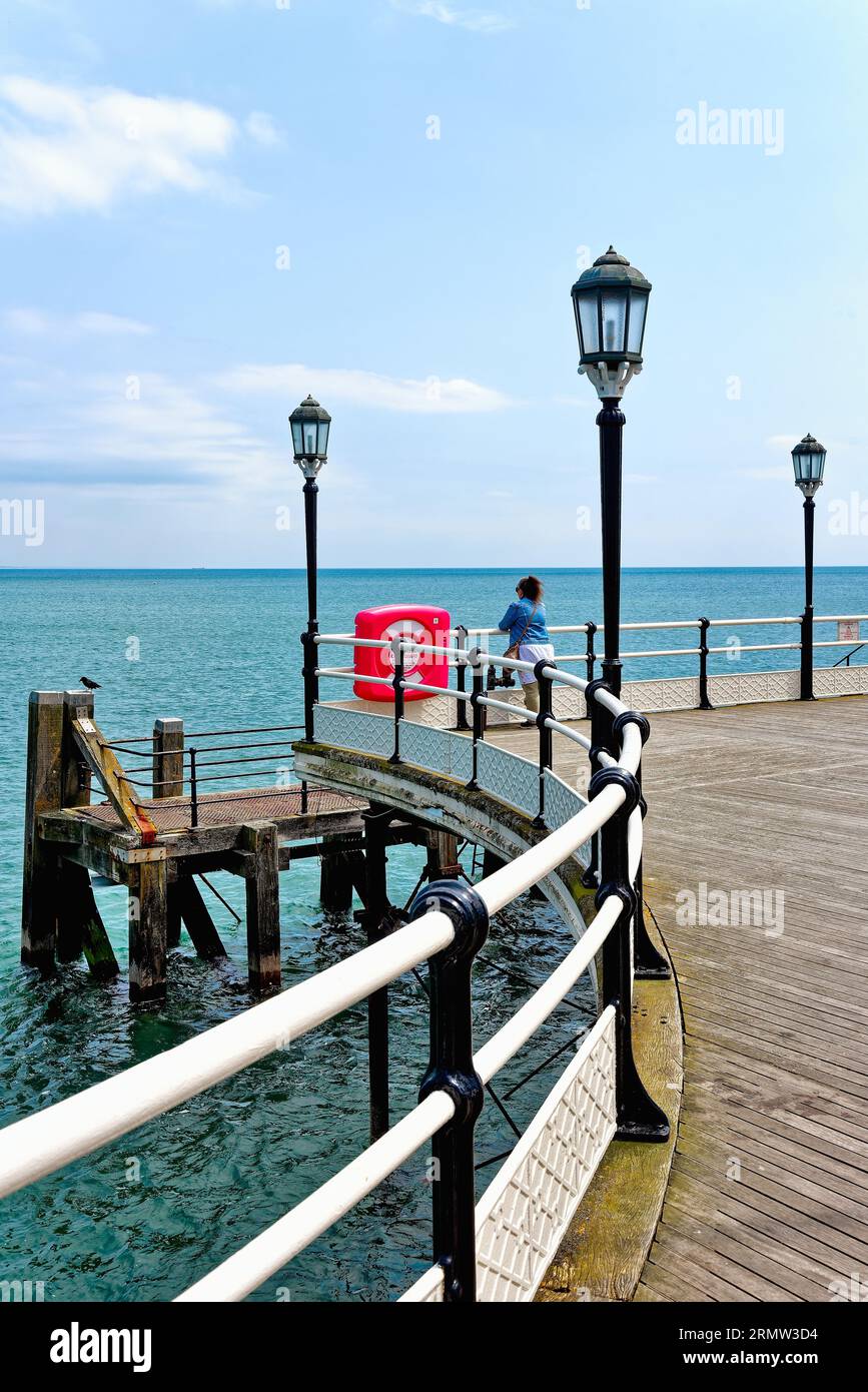 Une figure féminine solitaire regardant vers la mer au bout de la jetée Worthing sur une journée claire d'été Worthing West Sussex Angleterre Royaume-Uni Banque D'Images