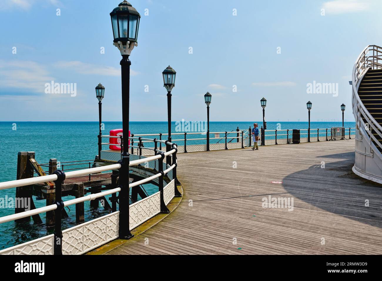 Une figure féminine solitaire regardant vers la mer au bout de la jetée Worthing sur une journée claire d'été Worthing West Sussex Angleterre Royaume-Uni Banque D'Images