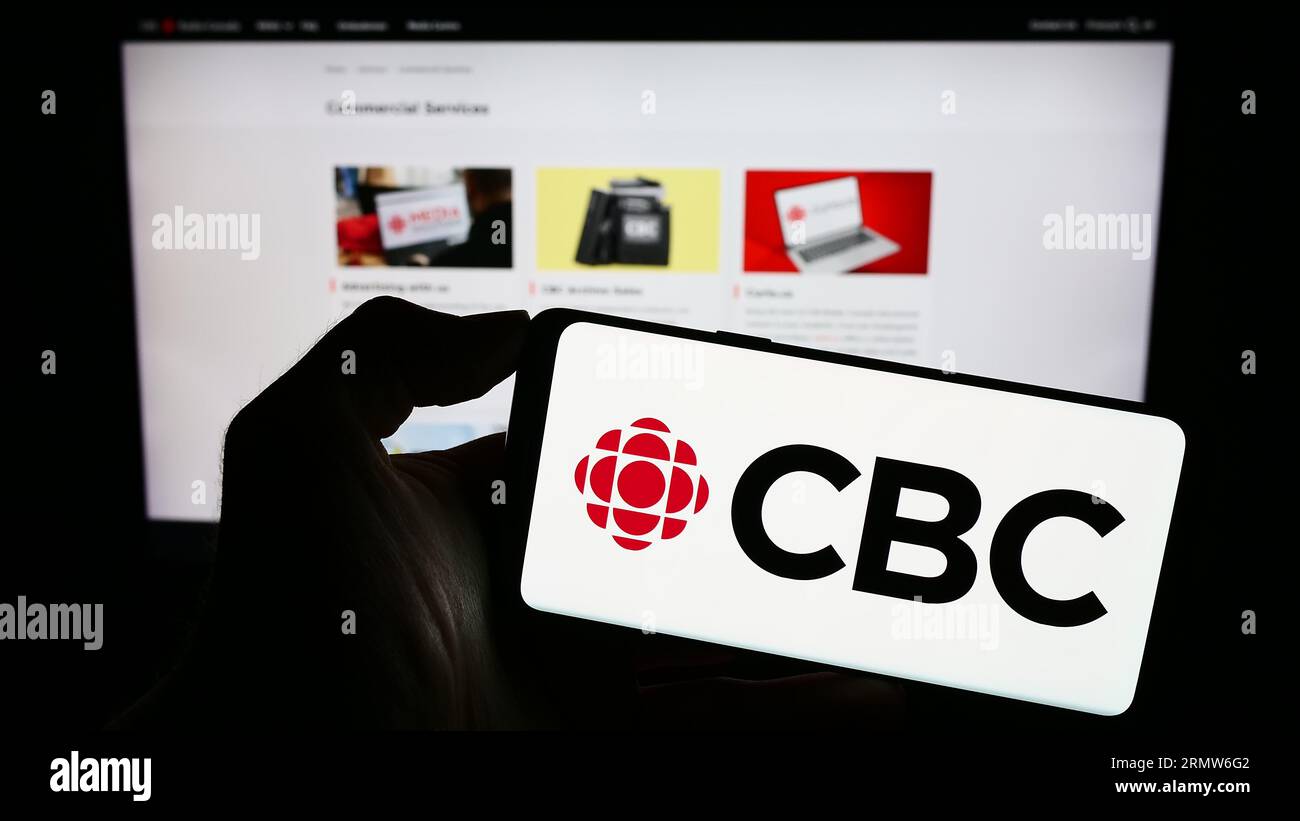 Personne détenant un téléphone cellulaire avec le logo de la Société radio-Canada (SRC) à l'écran devant la page Web. Concentrez-vous sur l'affichage du téléphone. Banque D'Images Personne détenant un téléphone cellulaire avec le logo de la Société radio-Canada (SRC) à l'écran devant la page Web. Concentrez-vous sur l'affichage du téléphone. Banque D'Images