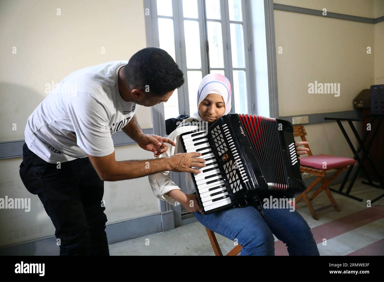 Le Caire, Égypte. 27 août 2023. Un instructeur enseigne à une fille comment jouer de l’accordéon pendant un cours de musique à la Maison de l’Art et de la Culture au Caire, en Égypte, le 27 août 2023. POUR ALLER AVEC 'Feature : une école de musique à but non lucratif au Caire offre des opportunités de changement de vie pour les jeunes défavoriséss' crédit : Ahmed Gomaa/Xinhua/Alamy Live News Banque D'Images