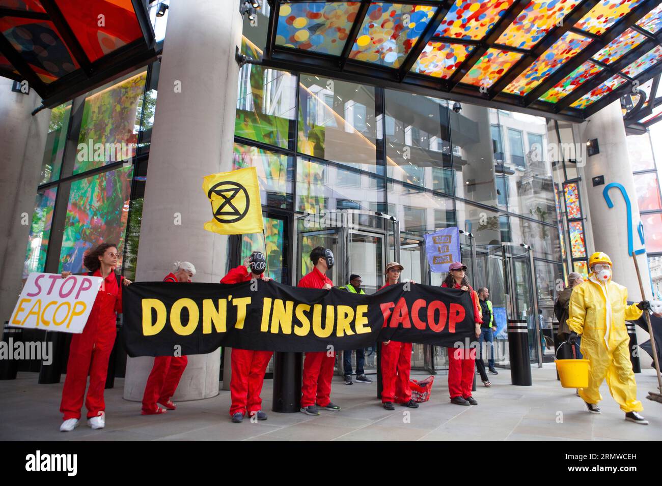 Londres, Royaume-Uni. 30 août 2023. Extinction les manifestants de la rébellion ont ciblé 10 compagnies d'assurance dans la ville de Londres, les exhortant à ne pas assurer l'East Africa Crude Oil Pipeline (EACOP). « Oil Slickers » en noir et blanc défilait silencieusement dans les rues et devant chaque compagnie d'assurance, de l'huile symbolique (fausse) était versée sur un globe avant d'être nettoyée par une équipe en combinaisons Hazmat. Crédit : Anna Watson/Alamy Live News Banque D'Images