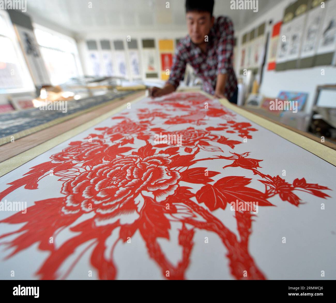 (141022) -- CHAOYANG, 22 octobre 2014 -- Un artisan travaille dans un atelier du sous-district de Hongshan dans le comté de Jianping, province du Liaoning au nord-est de la Chine, 22 octobre 2014. La coupe de papier, l'art folklorique chinois traditionnel qui utilise le papier rouge comme matériau pour faire des images avec des ciseaux, a été transférée de génération en génération dans le comté de Jianping et s'est maintenant développé en une industrie culturelle. Bai Tiejun) (wyl) CHINA-LIAONING-JIANPING-PAPER CUT INDUSTRY (CN) BaoxTiejun PUBLICATIONxNOTxINxCHN Chao Yang OCT 22 2014 a travaux dans un atelier dans le Hong Shan du comté de Jian Ping Nord-est C Banque D'Images