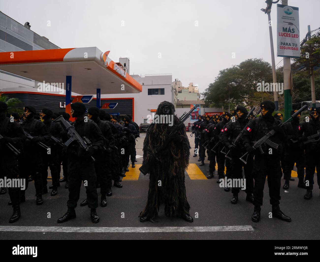 Lima, Pérou - juillet 29 2023 : jeune homme péruvien peignant noir portant des vêtements de camouflage de buissons et de saleté, tenant un pistolet dans le jour de l'indépendance Mil Banque D'Images