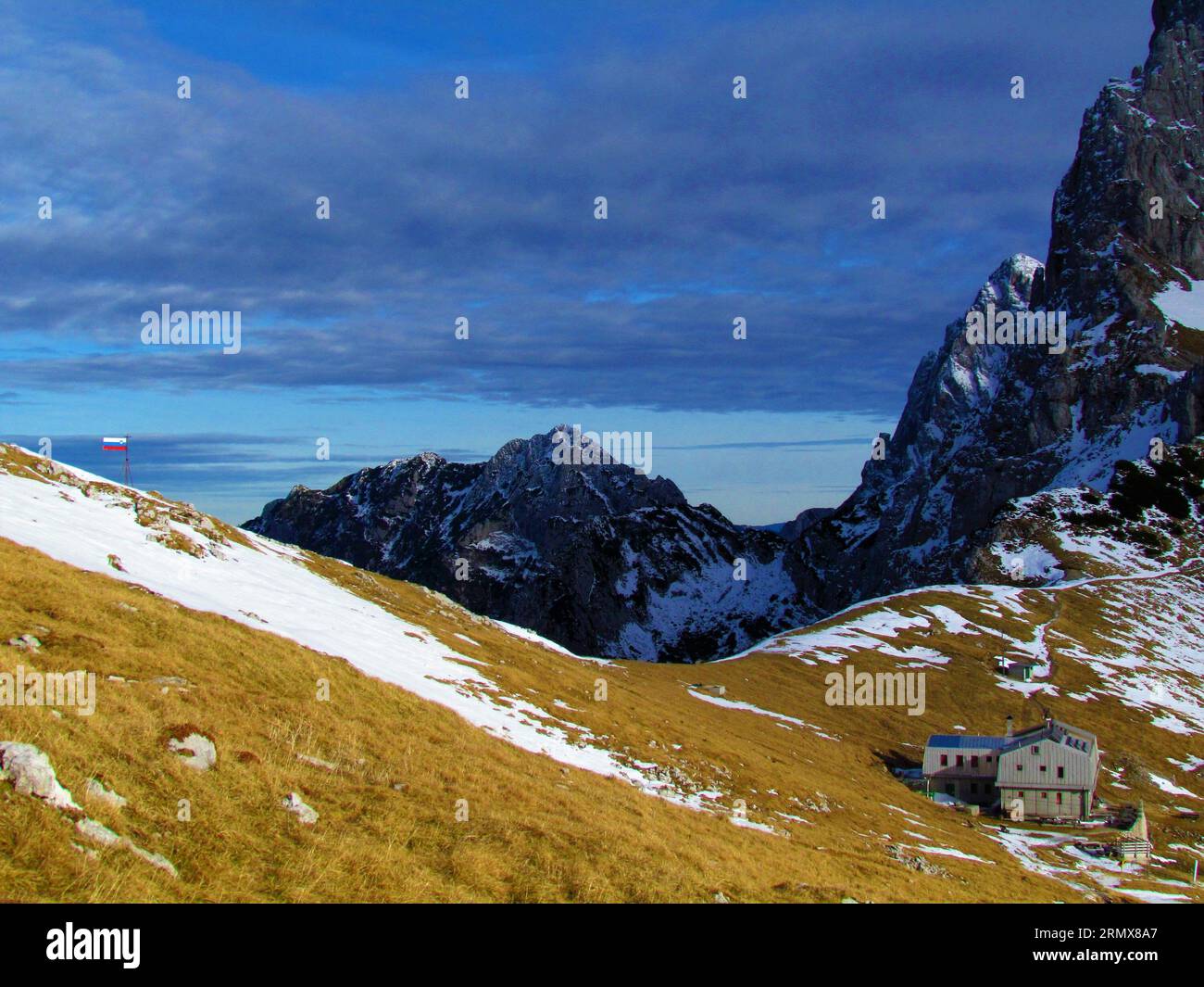 Vue panoramique de la montagne Krofička à l'arrière et le soleil éclairé les pentes herbeuses de Kamnisko sedlo et la cabane à Kamnisko sedlo en face en hiver à Kamnik-SAV Banque D'Images