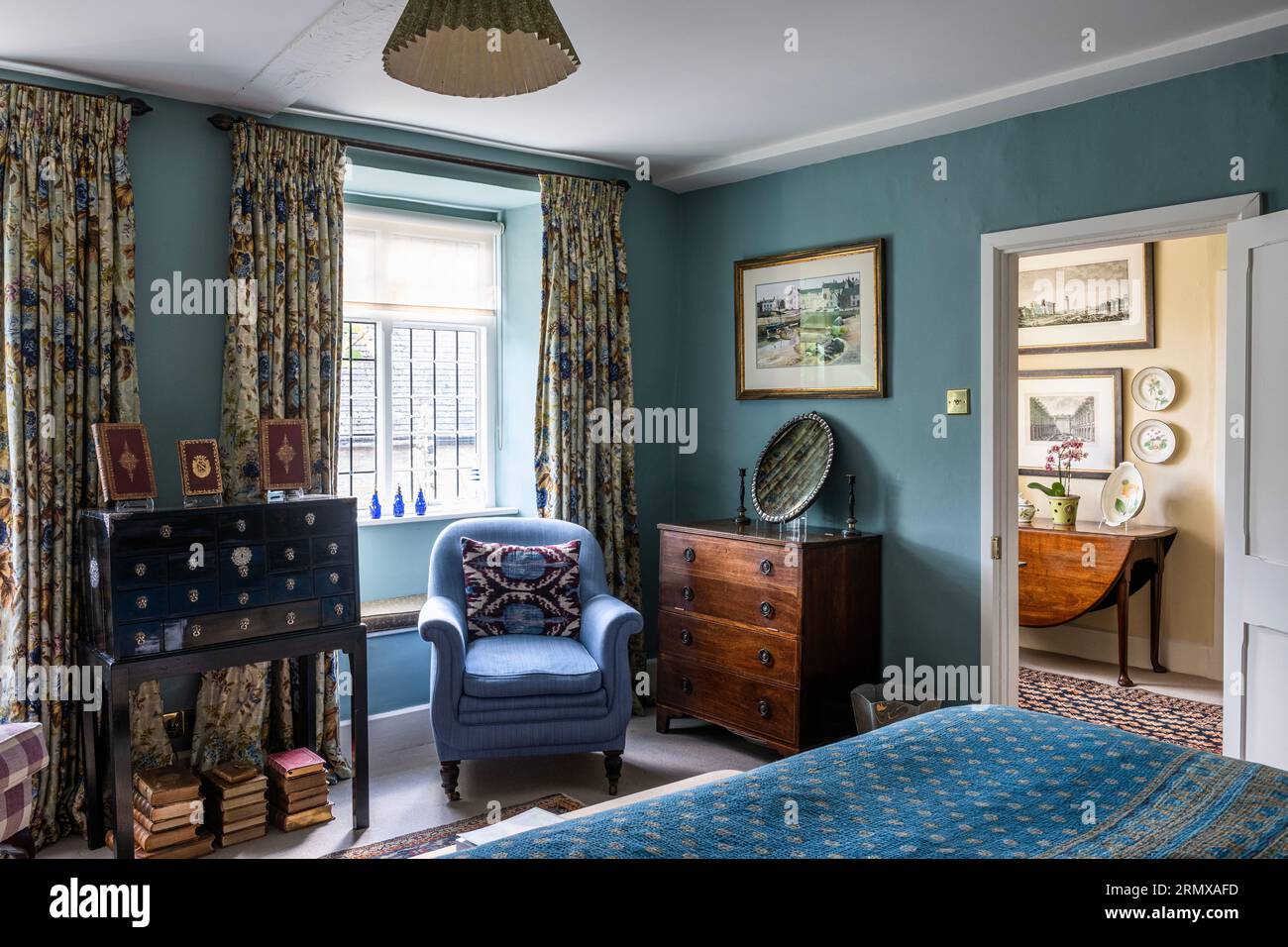 Fauteuil bleu dans la fenêtre avec tiroirs anciens et kantha indien dans la maison géorgienne du 18e siècle, Northamptonshire, Royaume-Uni Banque D'Images