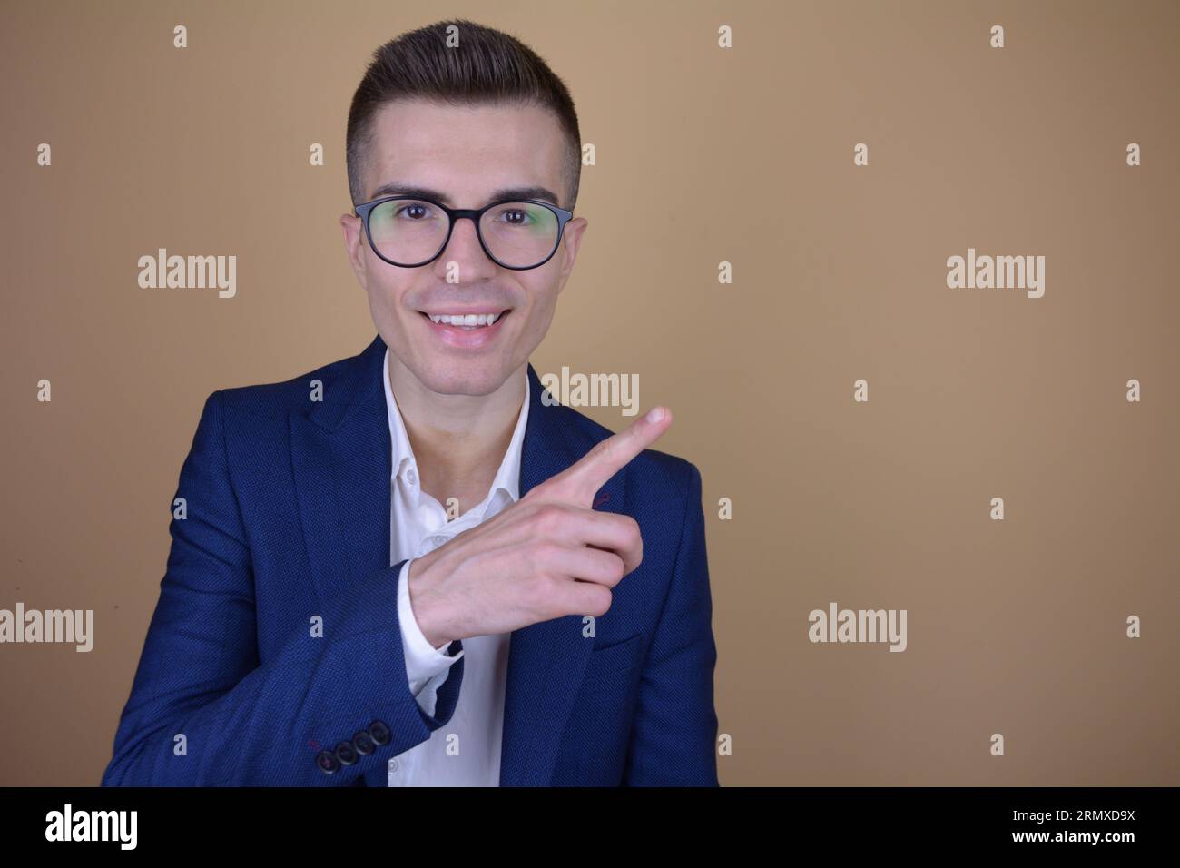 Sourire Jeune bel homme élégant pointant doigt sur le côté à Copy Space sur fond isolé Banque D'Images